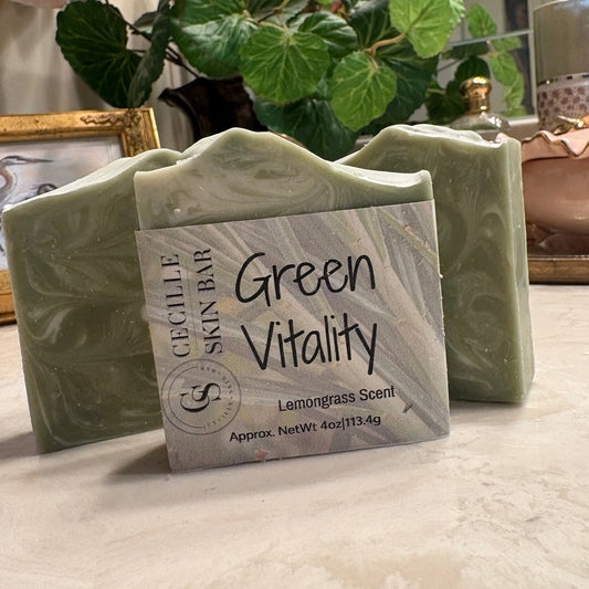 A bar of Cecile Skin Bar soap labeled 'Green Vitality Lemongrass Scent' in a sage green marbled finish, displayed on a marble countertop with a potted plant in the background.
